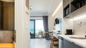Una cocina moderna con lavavajillas integrado, un comedor con mesa y sillas, y vista al exterior a través de una puerta de vidrio.