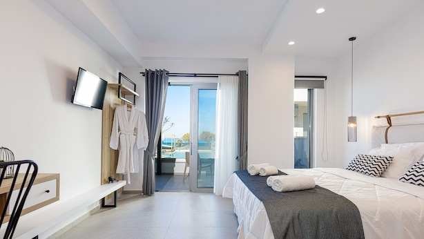 Habitación de hotel moderna con cama, escritorio, televisor y vista a la piscina.