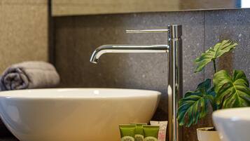 A bathroom with a large white sink, a modern faucet, and a potted plant.