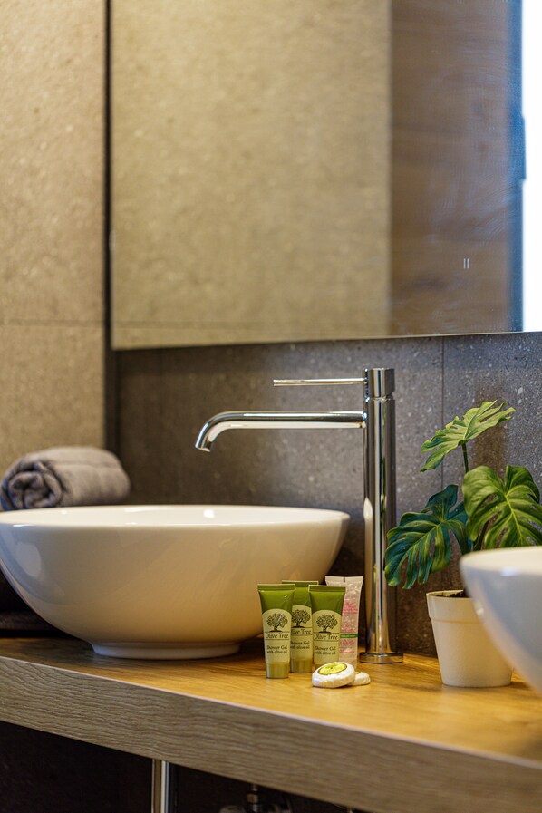 A bathroom with a large white sink, a modern faucet, and a potted plant. - Eleven Boutique Suites (Rethymno)