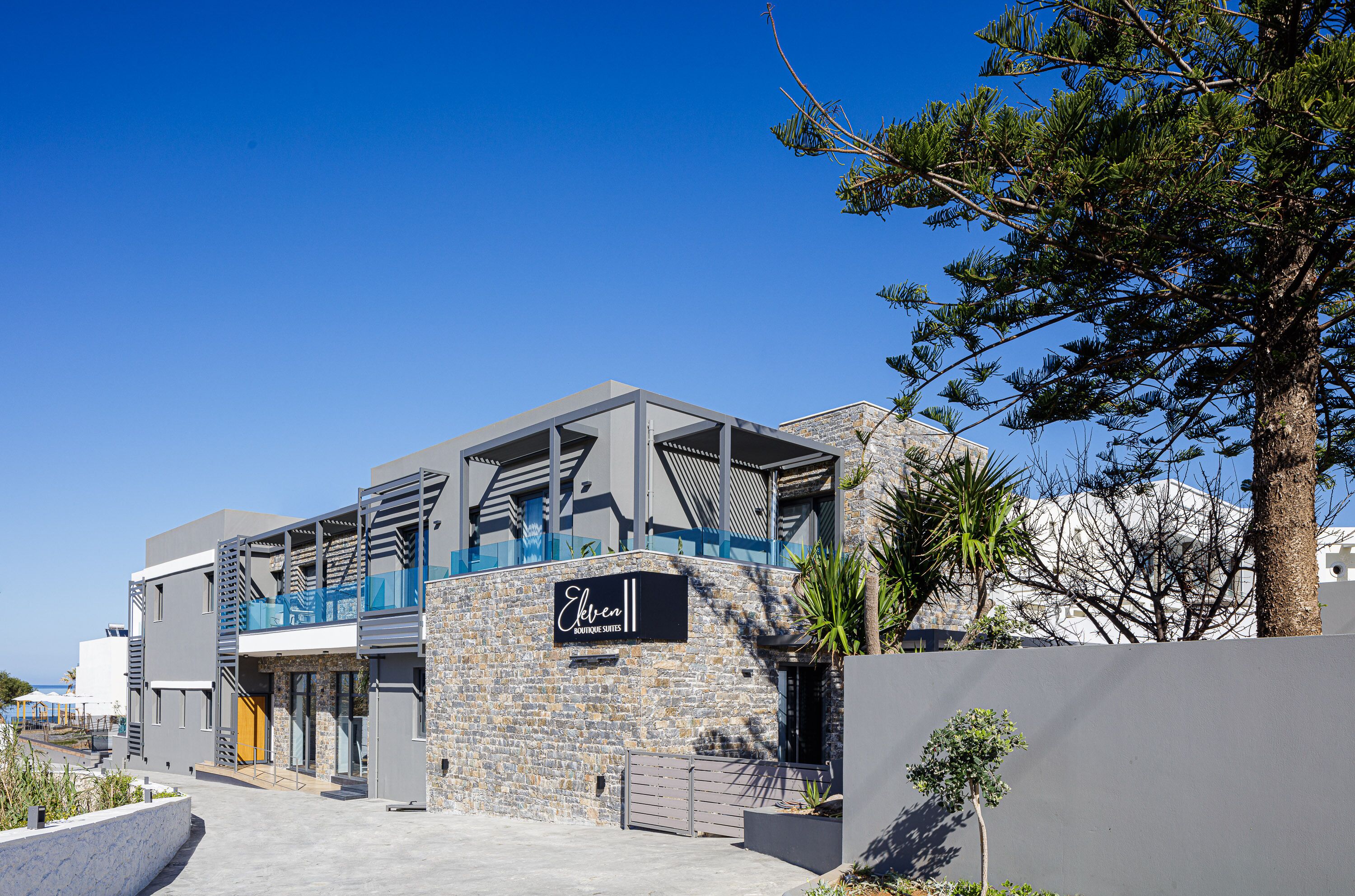 A modern building with a stone facade, a prominent sign, and a clear blue sky.