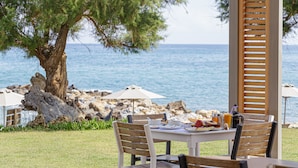 Un área de comedor al aire libre con una mesa lista para el desayuno, con vistas al mar.