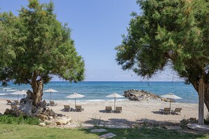 En la playa, sillas reclinables de playa, sombrillas, toallas de playa