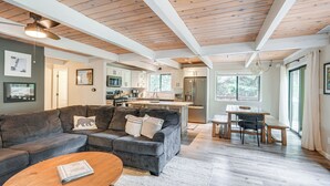Un salon moderne avec un canapé d’angle, une table basse en bois et un coin repas comprenant une banquette et une table.