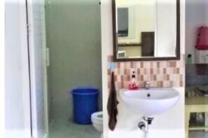 A bathroom with a white sink, a mirror, and a blue trash bin. - Dewina Villas (Batu)