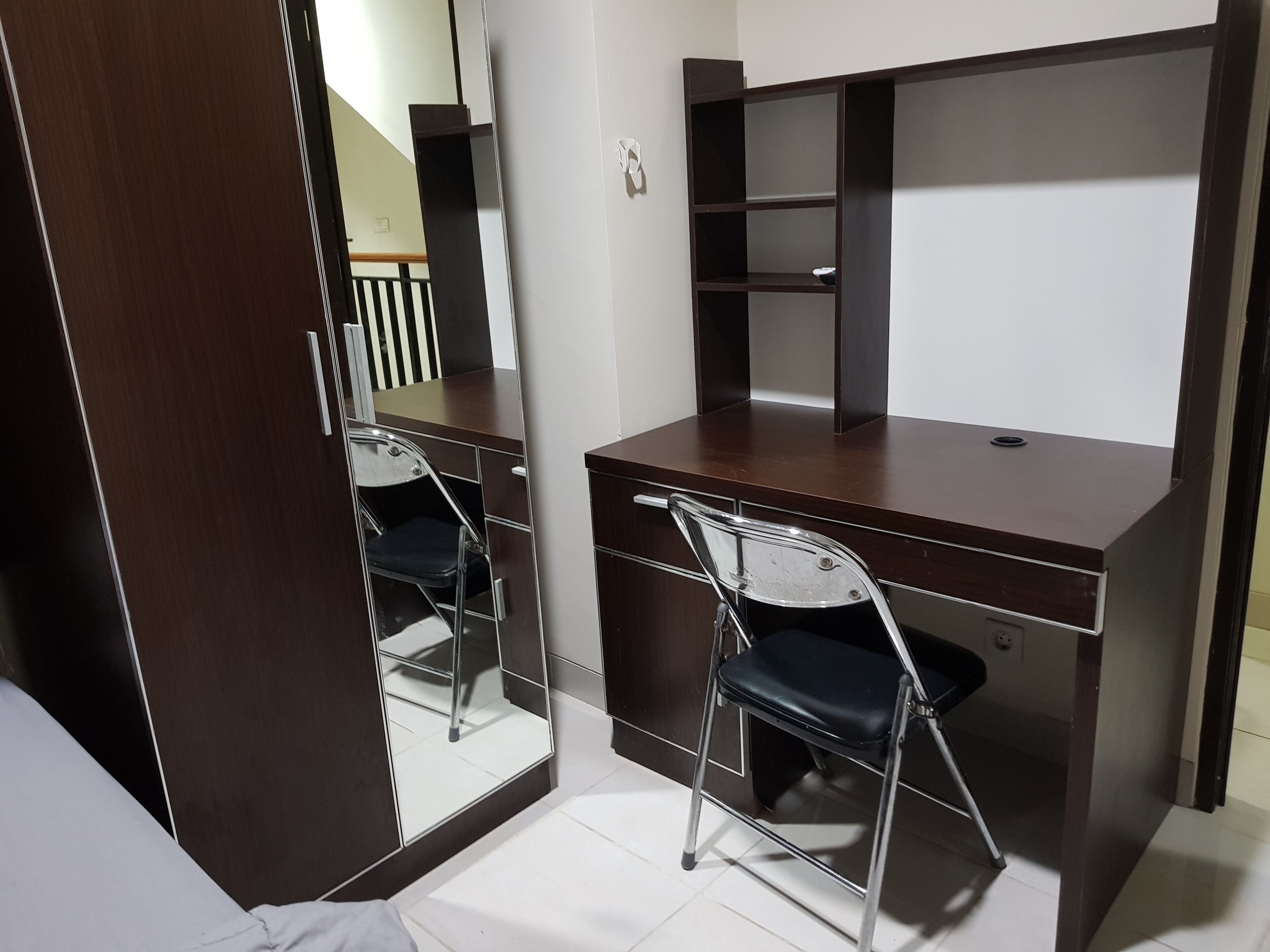 A compact room with a desk, chair, and a large mirror.