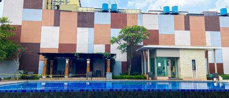 A modern building with a checkered facade, a swimming pool, and a small adjacent structure.