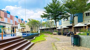 A courtyard with a swimming pool, outdoor seating, and a statue. - Aloha Guest House 2 (Gading Serpong)