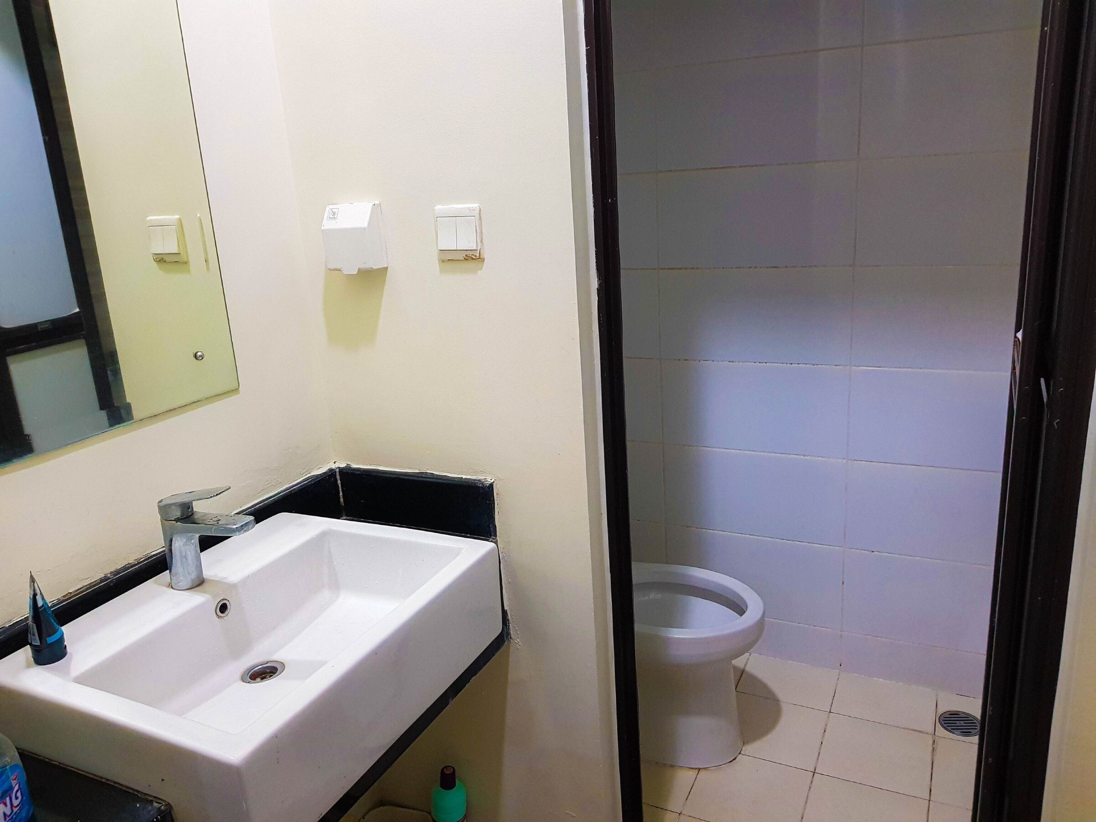 A bathroom with a white sink, a mirror, and a toilet.