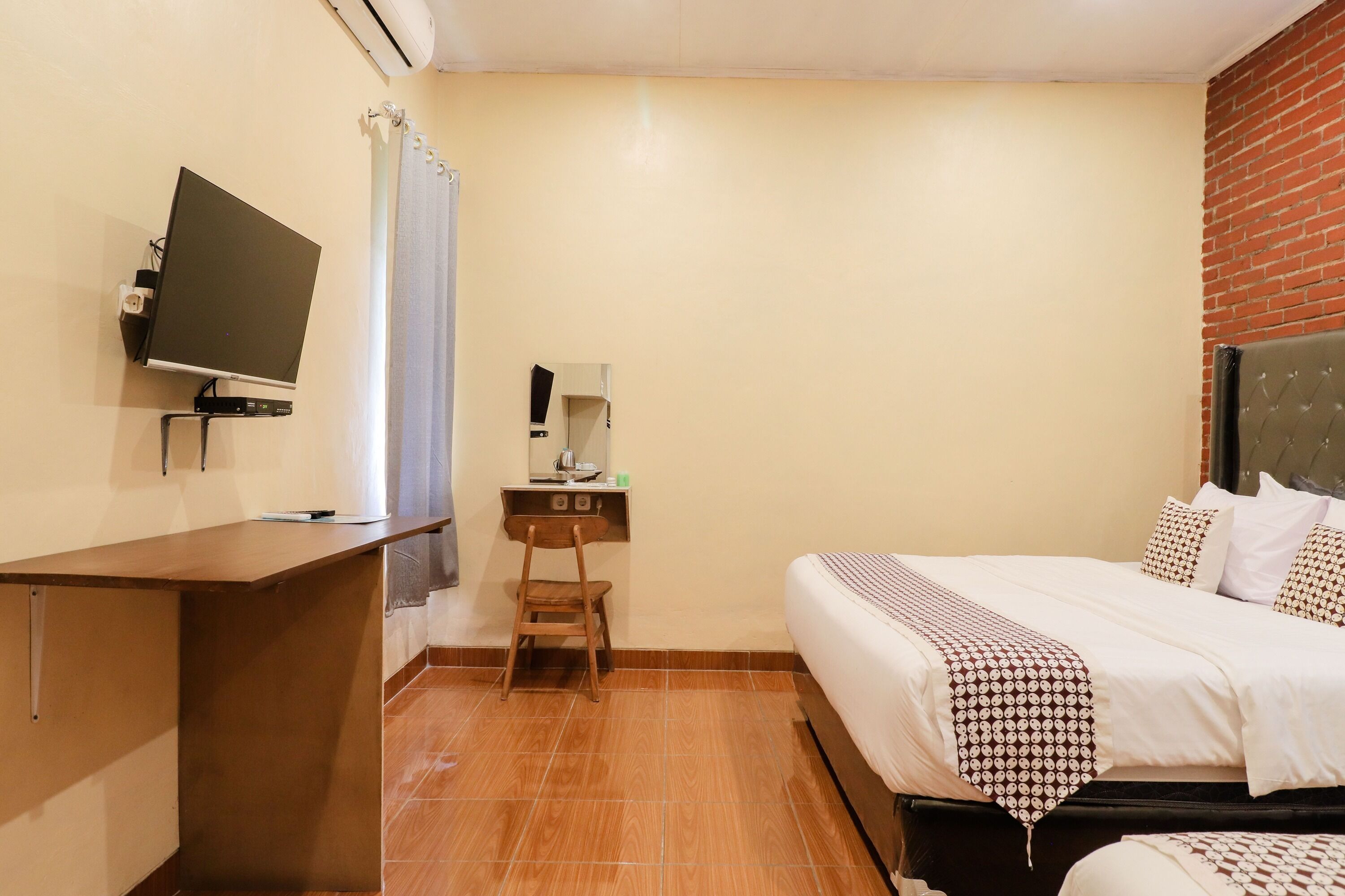A hotel room with a bed, a desk, a television, and a small table with a lamp.