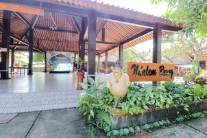 Un espacio al aire libre cubierto con un letrero que dice 'Nikelam Bory' y una gran estatua de Buda.