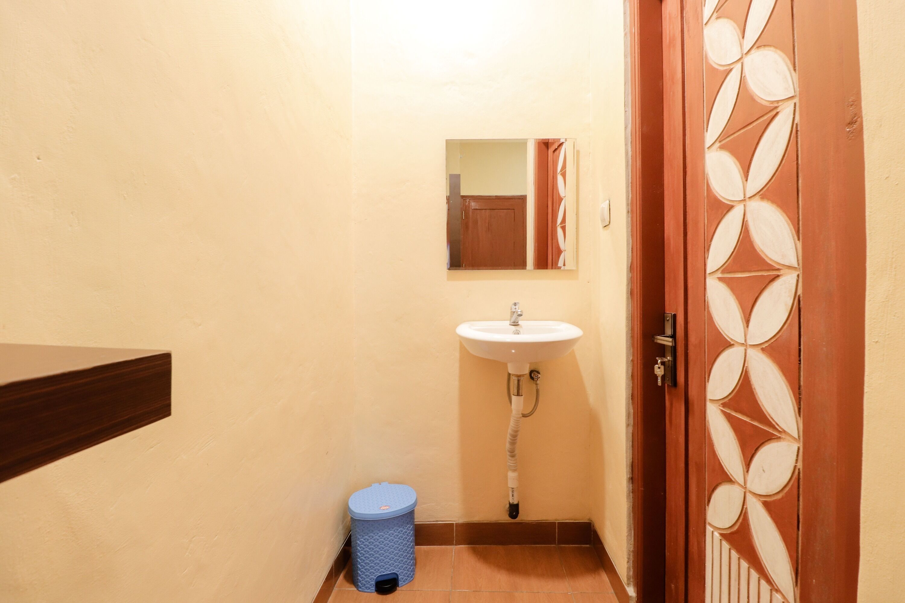 Un baño con lavamanos, espejo y cubo de basura.