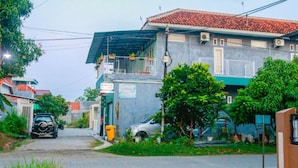 A residential street with houses, a paved road, and parked cars. - Kozi Kost Paviliun (Tegal)