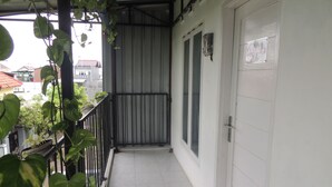 A narrow corridor with a tiled floor, a metal railing, and a door with a sign. - Kozi Kost Paviliun (Tegal)