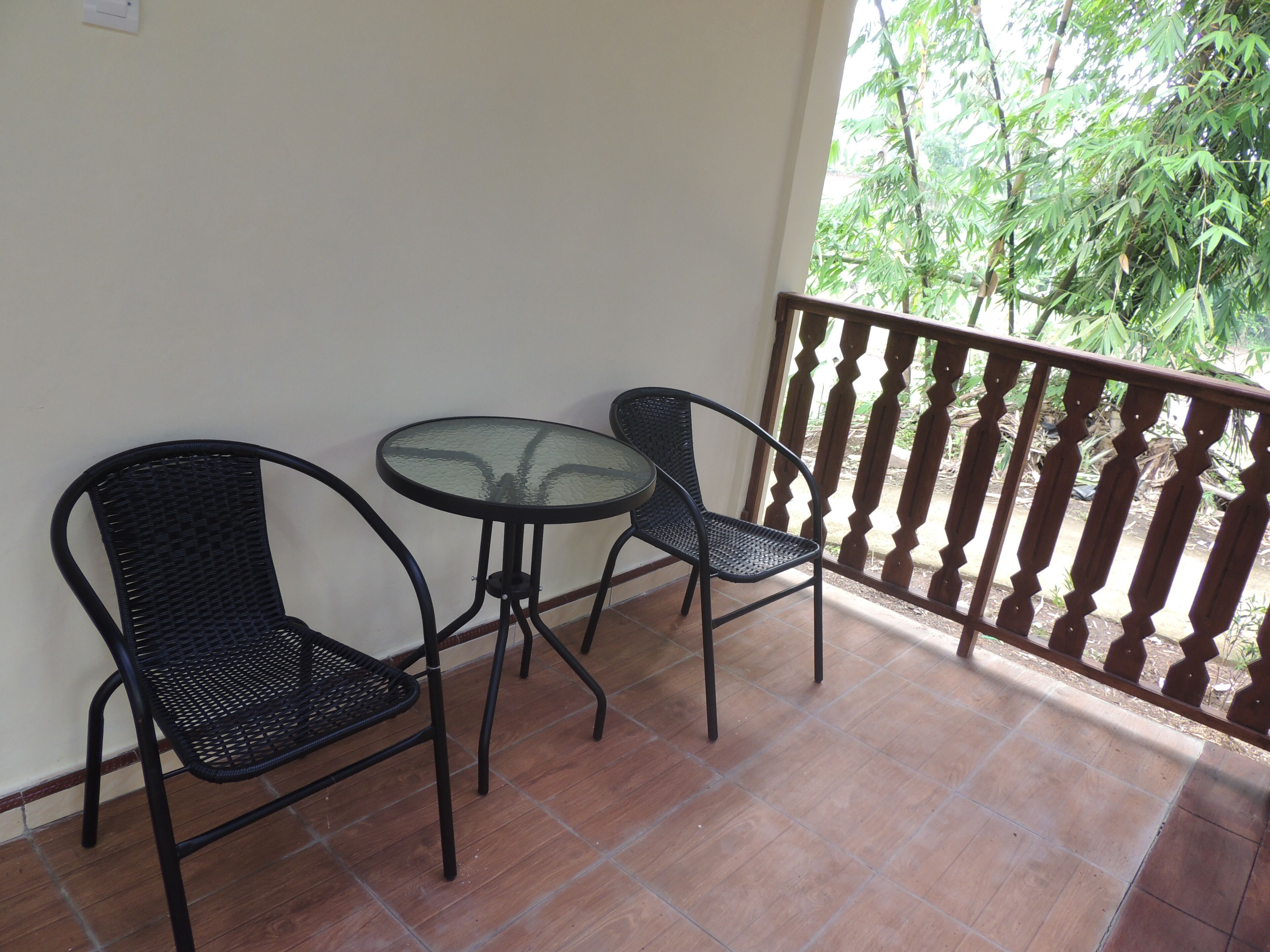 A balcony with two metal chairs and a glass table.
