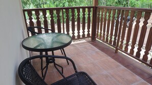 A balcony with a glass table and wicker chairs, surrounded by a wooden railing. - Srikayah by Ndalem Beong (Borobudur)