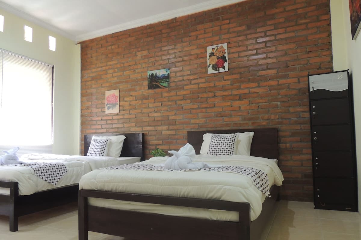 A hotel room with two beds, a brick wall, and a door.