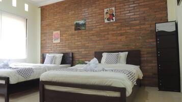 Habitación de hotel con dos camas, una pared de ladrillo y una puerta.
