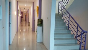 A hallway with a staircase, light-colored walls, and a purple railing.