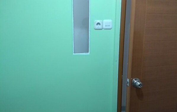 A door with a frosted glass panel and two wall-mounted light switches. - Eiffel Residence Cideng - Female Only (Jakarta)