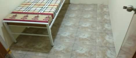 A narrow hallway with a metal table covered by a checkered tablecloth. The floor is tiled with a marble-like pattern.