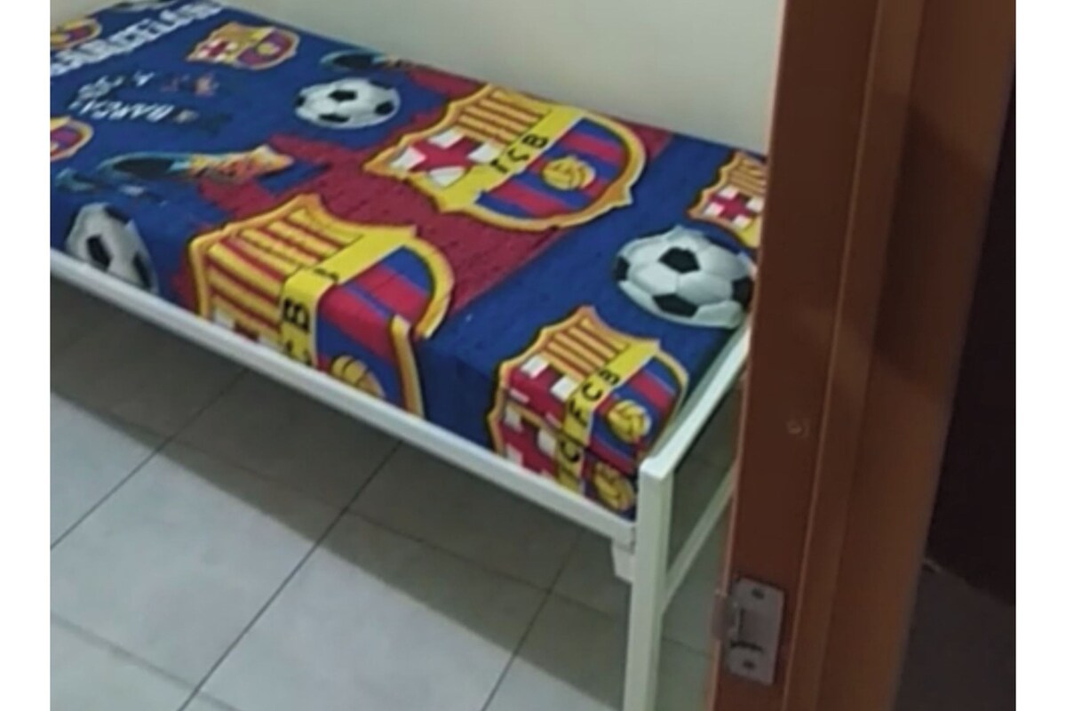 Un lit simple avec un matelas bleu et une couette aux couleurs du club de football de Barcelone.