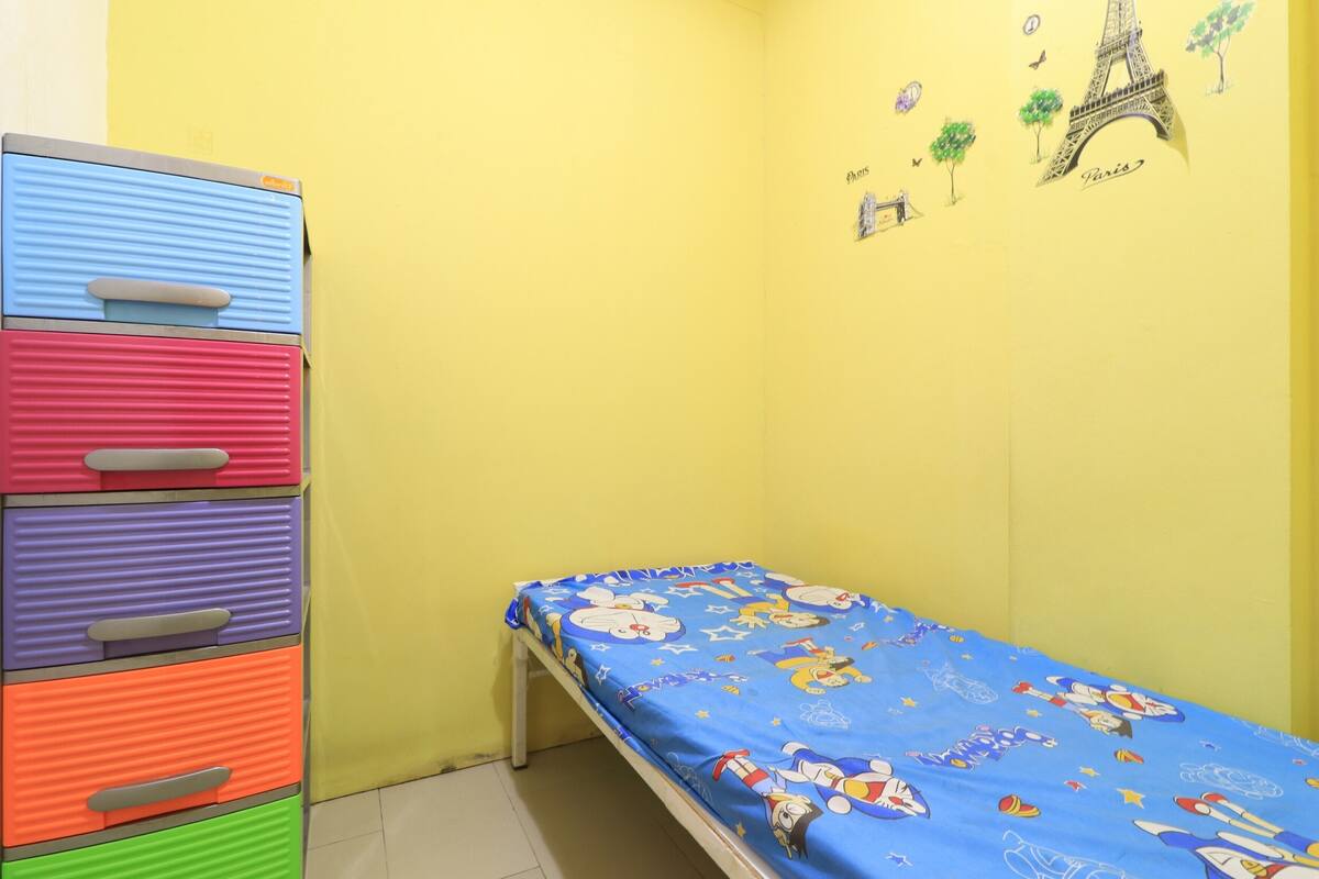 Een kleine kamer met een bed, een kleurrijke dressoir en een muur versierd met Parijse decoraties.