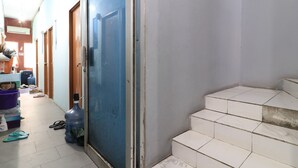 Ein Flur mit einer blauen Tür, einem Wasserspender und einer Treppe, die zu einer oberen Etage führt.