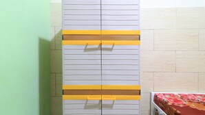 Een kamer met een bed, een garderobe met horizontale handgrepen en een groene wand.
