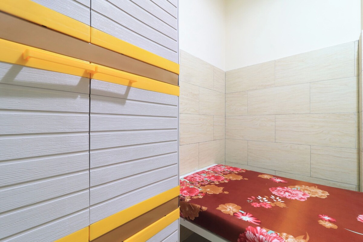 Una habitación con una cama, una pared con líneas horizontales y una pared con azulejos.