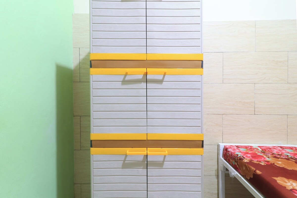 Una habitación con cama, un armario de tiradores horizontales y una pared verde.