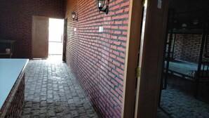 Una habitación con pared de ladrillo, puerta de madera y suelo de piedra.