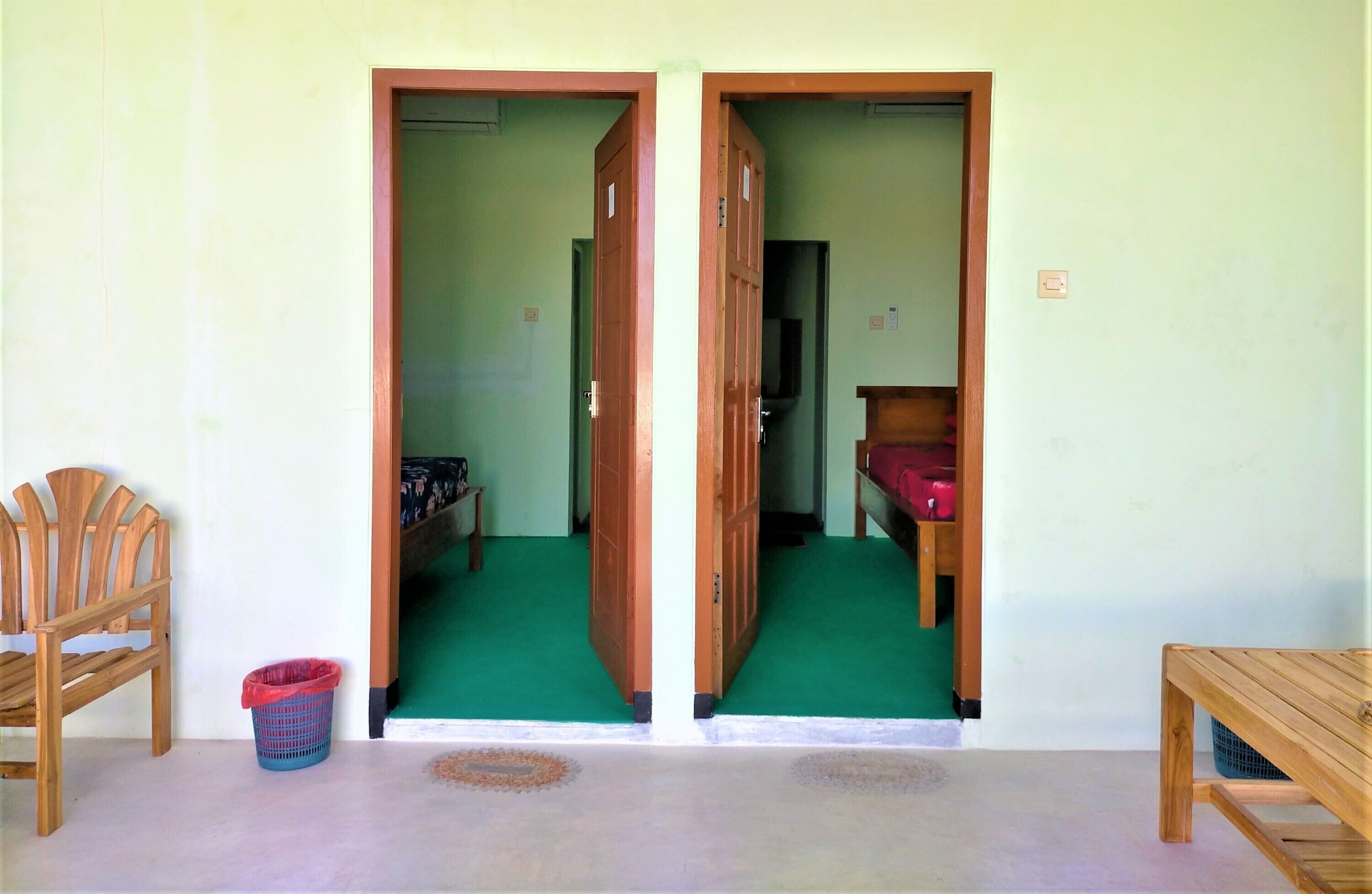 A room with a green carpet, wooden furniture, and a visible door leading to another room.