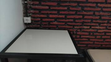 A corner of a room with a white table and a brick wall.