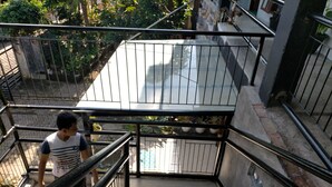 Una escalera con barandillas de metal y piso de concreto, que desciende a un nivel inferior.