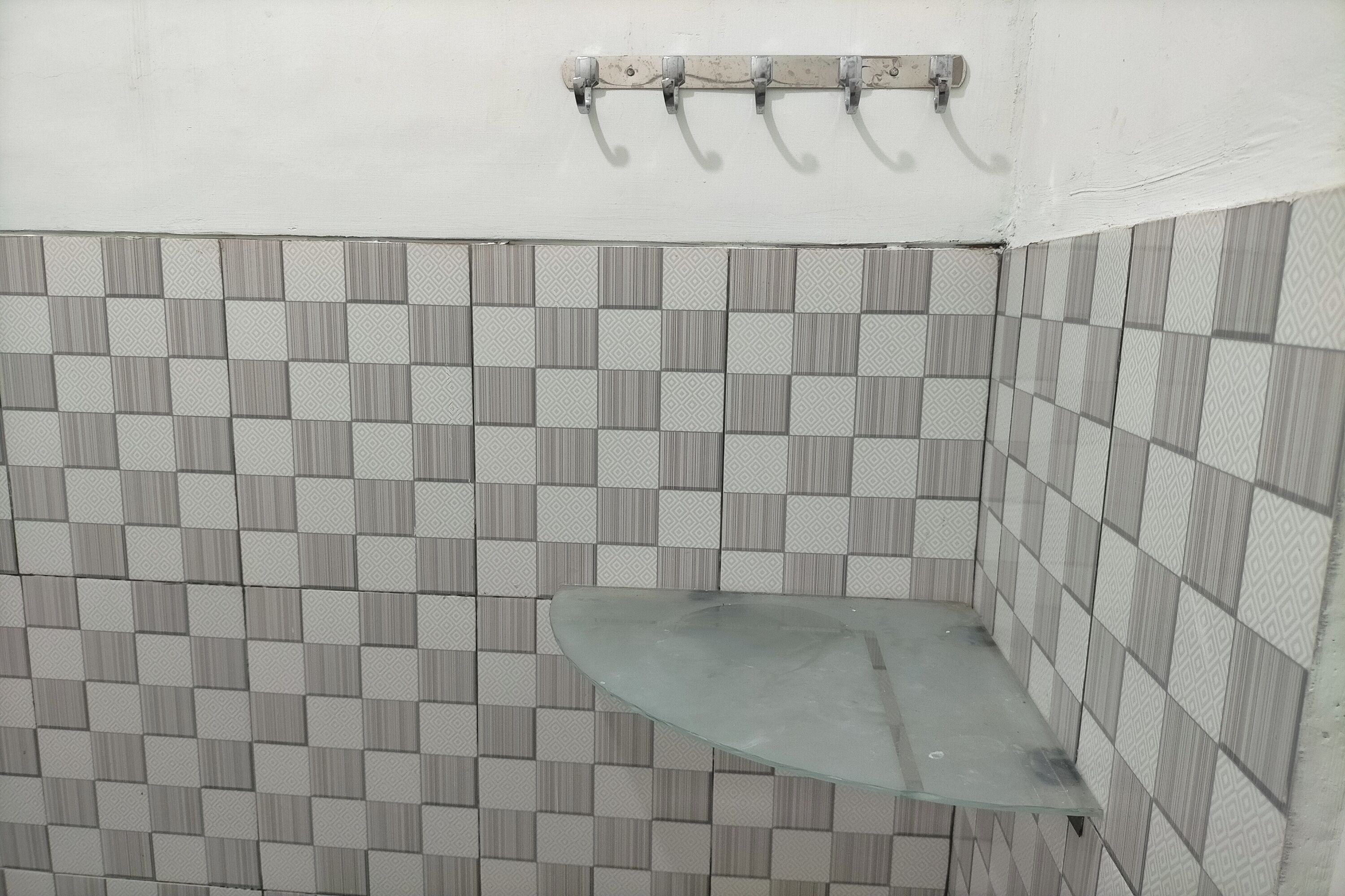 A bathroom with a tiled floor and walls, a glass shower enclosure, and a towel rack above the wall.