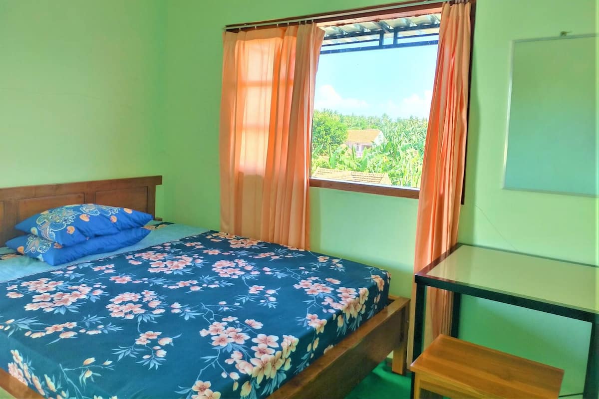 Un dormitorio con cama, cabecera de madera, ventana con cortinas y una mesita de noche.