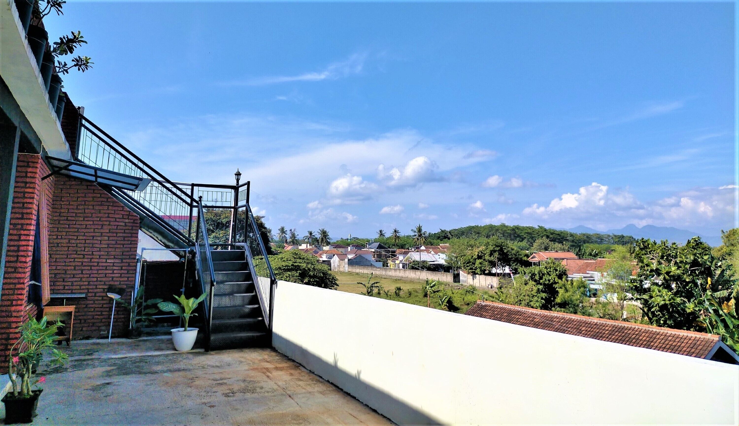 A staircase leading to a building with a view of a residential area and mountains in the distance.
