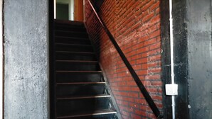 Una escalera con barandilla negra y paredes de ladrillo rojo.