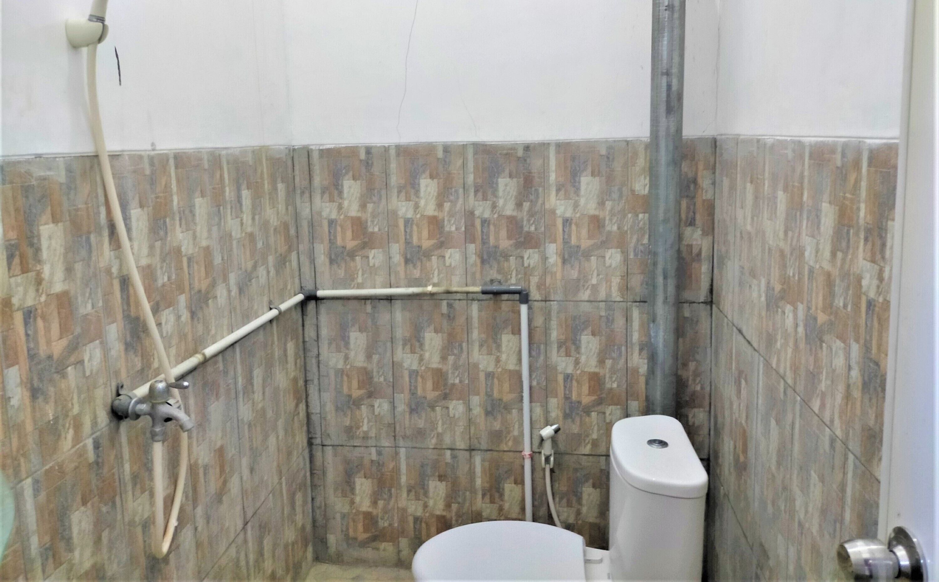 Ein kleines Badezimmer mit Fliesen, einer Toilette, einer Duschkabine und einem Händetrockner.