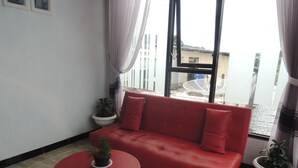A red sofa with cushions, a red round table with a plant, and two potted plants.