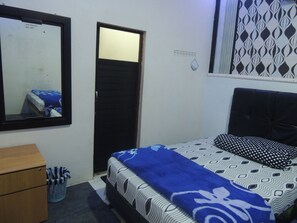 Une chambre à coucher avec un lit, une commode, un miroir, une porte et un rideau à motifs.