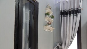 A room with a window, a curtain, and a shelf with decorative items.