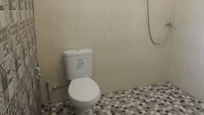 Pieni kylpyhuone, jossa on wc, suihku ja kuvioituja laattoja.