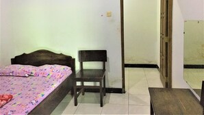 Un dormitorio con cama, una silla, un espejo y una puerta.