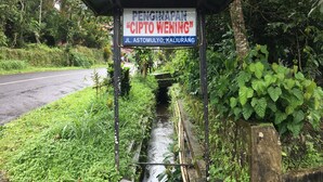 Un cartel con la leyenda "PENGINAPAN" y "CIPTO WENING", situado al lado de una carretera con vegetación.