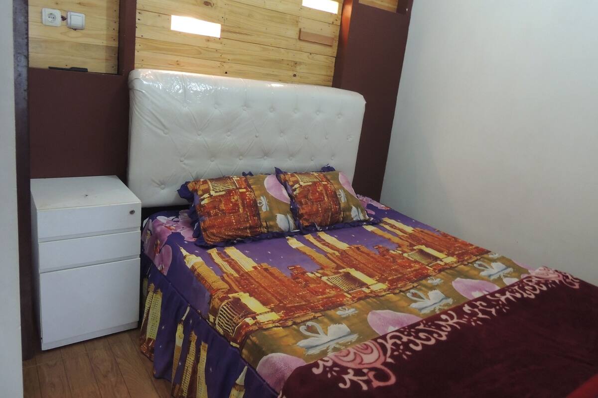 Quarto com uma cama, uma mesinha de cabeceira e uma cabeceira de madeira.