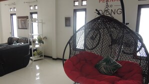 Una habitación con un sofá de cuero negro, un sillón orejero rojo y un piso de baldosas blancas. Hay una pared con un letrero que dice '# PERMANENT # KEY # DING'.
