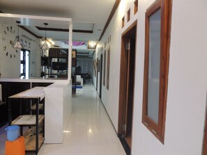 A modern kitchen with white cabinets, a central island, and a dining area with a table and chairs. - Puspa Indah Syariah 1 (Dieng Kulon)