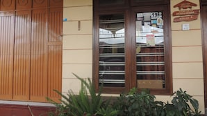 Fachada de edificio con puerta de madera, ventana con un cartel y una señalización que indica una casa de huéspedes.